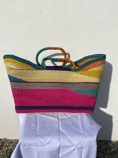 a multicolored straw bag sitting on top of a white cloth covered chair next to a wall