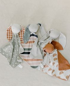 several baby bibs laying next to each other on a white surface, one with an orange and green striped bib