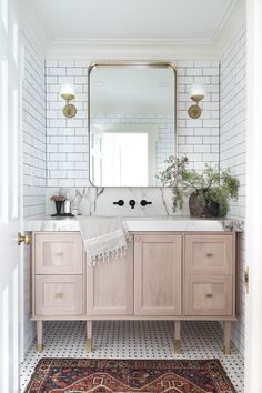 a bathroom with white brick walls and wooden vanity, rug, and large mirror on the wall