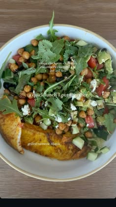 a white plate topped with a salad covered in lots of greens and chickpeas