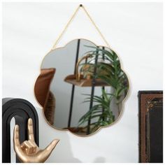 a mirror hanging on a wall next to a hand and potted plant in front of it