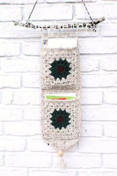 two crocheted christmas decorations hanging on a brick wall next to a white brick wall