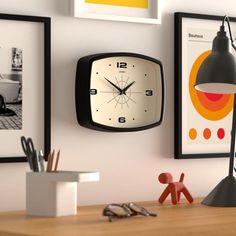 there is a clock on the wall next to some framed pictures and a desk lamp