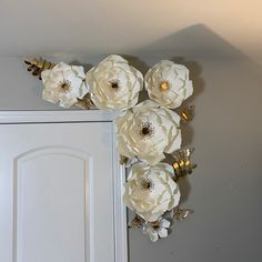 white paper flowers are hanging on the wall next to a door with gold trimmings