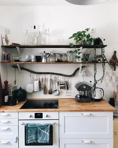 a kitchen with white cabinets and shelves filled with pots, pans and utensils