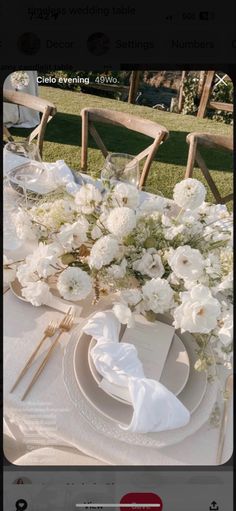 the table is set with white flowers and place settings