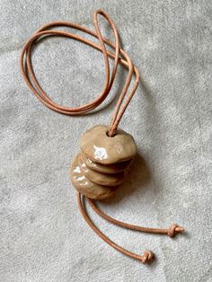 "Simplicity and repose are qualities that measure the true value of any work of art..." So said Frank Lloyd Wright, and who are we to argue with that notorious crank? Anyway. We love the repose of this necklace by Elise Birnbaum of Oatmeal Ceramics. The elements: ceramic and and leather. The form: simplicity itself. Cairns to mark the way on your path. This may be statement piece in scale, but there’s a subtlety in its refined restraint. Simplicity and repose indeed. 1.5" pendant on a 40" leather cord. Adjustable Earthy Necklace For Everyday Wear, Adjustable Large Pendant Necklace For Everyday, Adjustable Everyday Necklace With Large Pendant, Everyday Adjustable Necklace With Large Pendant, Artisan Round Pendant Necklace For Everyday, Earthy Adjustable Round Pendant Necklace, Adjustable Earthy Pendant Necklaces, Artistic Adjustable Brown Necklace, Adjustable Brown Artistic Necklace