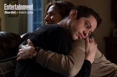 Edie Falco and Pete Davidson embrace as their characters in the new series 'Bupkis.' Pete's face looks solemn, in the forefront of the photo, while Edie's eyes are closed, hugging him tightly. She plays his mom in the series. Instagram, Pop, Version, Davidson