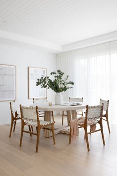 a white dining room with wooden chairs and a table