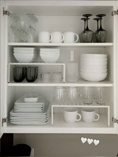 white dishes and cups are stacked on the shelves