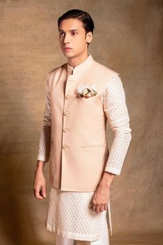 Soft pink bundi in italian polywool with button placket. Paired with white checkered kurta and trouser.
Components: 3
Neckline: Band collar
Sleeve Type: Bundi: Sleeveless, Kurta: Full
Fabric: Bundi: Italian polywool, Trouser: Cotton silk, Kurta: Self chanderi
Color: Pink, White
Other Details: 
Button placket
Side slits
Note: The pocket squares worn by the model is not for sale
Occasion: Mehendi and Puja - Aza Fashions Elegant Pink Long Sleeve Nehru Jacket, Designer Nehru Jacket With Stand Collar For Semi-formal Occasions, Designer Nehru Jacket With Stand Collar For Work, Designer Nehru Jacket For Semi-formal Occasions, Traditional Bandhgala With Buttons For Workwear, Fitted Bandhgala With Stand Collar And Button Closure, Fitted Bandhgala With Button Closure And Stand Collar, Elegant Pink Nehru Jacket For Festive Occasions, Elegant Festive Bandhgala With Button Closure