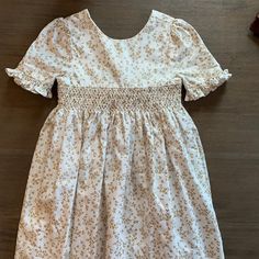 New Luli And Me Gold Leaf Smocked Dress. It's A White Background With A Metallic Gold Leaf Pattern All Over. It's A Simple Smocked Plate Across The Chest. The Arms Have A Small Ruffle At The Hem And There Is A Bow On The Back. All Of My Items Come From My Children's Boutique And Are Brand New, Directly From The Manufacturer. Please Feel Free To Ask Any Questions. White Smocked Dress With Floral Print And Short Sleeves, Cute White Smocked Dress With Short Sleeves, Cute White Dress With Smocked Back, Cute White Smock Dresses, Cute White Smocked Dress For Daywear, White Smocked Dress With Short Sleeves, White Ballerina Dress, Gold Holiday Dress, Red Holiday Dress