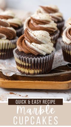 cupcakes with white frosting and chocolate icing are on a wooden tray