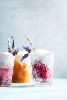 two glasses filled with different colored drinks on top of a white table next to each other