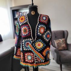 a colorful crocheted jacket on a mannequin in front of a chair