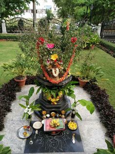 an arrangement of flowers and fruit on a table in the middle of a garden area