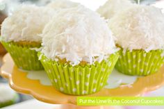 three cupcakes with white frosting and coconut toppings on a yellow plate