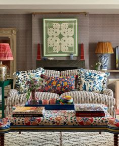 a living room filled with lots of furniture and pillows on top of a table next to a fire place