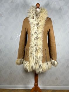 A beautiful coat made of fabric finished with fur imitating wild cat fur. Lovely pockets on the sides. The coat is in very good condition, no damage or unpleasant odors. Dimensions: sleeve from collar: 72 cm (measured without fur) sleeve from armpit: 40 cm (measured without fur) bust:2x45 cm in waist:2x 44 cm in the hips:2x 47 cm total length: 72 cm Our mannequin is size M. Brown Faux Fur Long Coat, Beige Hooded Fur Coat With Faux Fur Trim, Long Feather Trim Coat For Fall, Long Coat With Feather Trim For Fall, Fall Long Coat With Feather Trim, Brown Faux Fur Outerwear With Pockets, Brown Fur Coat With Faux Fur Trim, Brown Long Sleeve Fur Coat With Faux Fur Trim, Winter Feather Trim Fur Coat