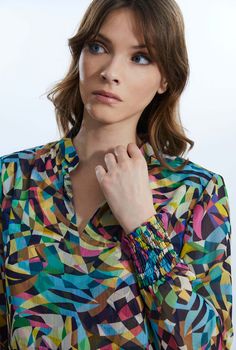 This chic yet bold printed blouse is a James Lakeland staple piece. Featuring its classic mandarin collar and short V-neck opening, long sleeves and elasticated cuffs. This chiffon blouse, lined in the same printed fabric has a slight sheer to it whilst being modest, with its shorter front and longer back panel which can be tucked-in or out.     Made in India 100% Polyester Machine Wash 30°C, Do not bleach, Do Not Tumble Dry. Spring Multicolor Blouse With Collared Neckline, Fitted V-neck Blouse With Smocked Cuffs, Spring Multicolor Blouse With Smocked Cuffs, Summer Multicolor Blouse With Smocked Cuffs, Fitted V-neck Blouse In Multicolor Print, Fitted V-neck Blouse With Vibrant Print, Multicolor V-neck Tops With Blouson Sleeves, Fitted Long Sleeve Blouse With Elastic Neckline, Multicolor V-neck Blouse With Blouson Sleeves