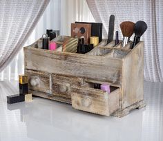 an old wooden box with makeup brushes and other items in it sitting on a white surface