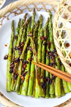 asparagus on a white plate with chopsticks and sauce in the bowl