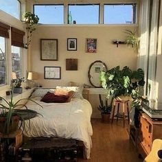 a bed sitting in a bedroom next to a window with lots of plants on it