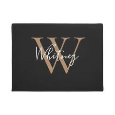 a black and gold door mat with the letter w in white on top of it