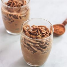 two glasses filled with chocolate pudding on top of a table