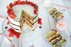 there is a cake that has been cut into pieces and placed on the table with strawberries