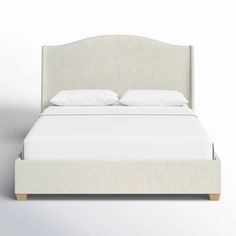 a bed with white sheets and pillows on it