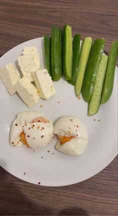 a white plate topped with cucumbers and eggs next to sliced up green beans