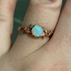 a woman's hand holding an opal ring