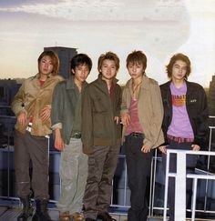 five young men standing on top of a building