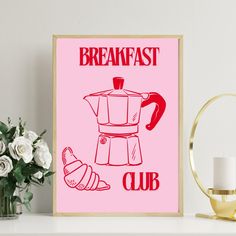 a pink poster with the words breakfast club on it next to a candle and flowers