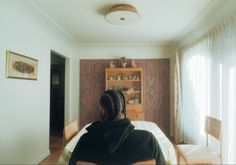 a woman sitting at a table in front of a dining room with chairs and a bookcase