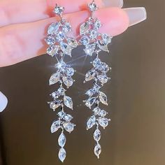 a pair of crystal earrings is being held by someone