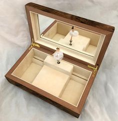 an open wooden box with miniature people in it on a white tableclothed surface