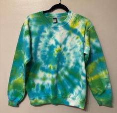 a green and blue tie - dyed sweatshirt hanging on a wall