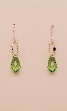 Peridot briolette drop earrings are pale green Swarovski crystals that dangle from shiny delicate silver tone ball chain and matching ball end ear wires. Created and designed by TLP from Takeen Arts. Item E411. Sterling Silver Faceted Earrings For May Birthstone, Green Faceted Sterling Silver Earrings, Green Nickel-free Teardrop Drop Earrings, Green Teardrop Drop Earrings Nickel Free, Green Sterling Silver Teardrop Earrings, Green Nickel-free Teardrop Earrings, Nickel-free Green Crystal Earrings In Sterling Silver, Nickel-free Green Sterling Silver Crystal Earrings, Sterling Silver Briolette Earrings For Party