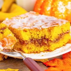 a piece of cake sitting on top of a white plate next to an orange pumpkin