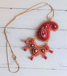 This  pretty pendant is based on a design by Nchantme but with my own design spin on it. I  have used  crystal cup chain, a crystal navette  and Czech fire-polish crystals as well as seed beads in red and gold and tiny red bells to  bead embroidered it. It is   made in 2 pieces, connected together so has lots   of movement  when you wear it, which heightens the  sparkle of the  materials I used.   The pendant is approx   4"/ 10 cm long and  2.5"/6 cm at its widest.    The chain is approx 20"/50c Gold Embellished Necklace For Gift, Gold Embellished Necklace Perfect For Gift, Bohemian Gold Embellished Necklace, Traditional Embellished Gold Necklace, Traditional Gold Embellished Necklace, Bohemian Pendant Beaded Necklaces With Gold Beads, Bohemian Beaded Necklaces With Gold Pendant, Bead Embroidered Pendant, Embroidered Pendant