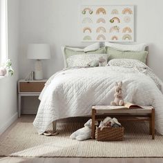 a bedroom with white bedding and green accents on the walls, along with two stuffed animals