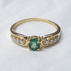 an emerald and diamond ring on a white surface