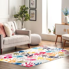 a living room with a couch, chair and rug on the hardwood floor next to a potted plant