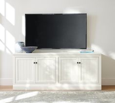 a flat screen tv sitting on top of a white cabinet