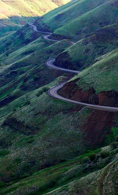 a winding road in the middle of green hills