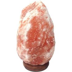 a large pink rock sitting on top of a wooden stand in front of a white background