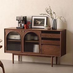 a wooden cabinet with glass doors and pictures on it's sides, next to a chair