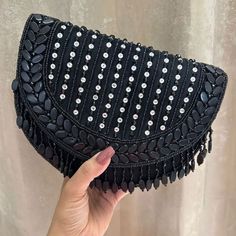 Introducing the Black Shefali Flap Bag, a stunning fusion of elegance and Indian craftsmanship. Hand-beaded with luxurious velvet in enchanting hues of Black, this bag embodies opulence and tradition. Its intricate design, coupled with delicate Black bead work, this makes it a standout accessory for brides and lovers of Indian fashion alike. Whether for a wedding ceremony or a cultural celebration, the Shefali Black Flap Bag adds a touch of regal charm to any outfit. Elevate your ensemble with the exquisite beauty of this Indian-inspired bridal bag. Materials used: Suede, Beading, Gold plated hardware At Romikas, we pride ourselves on the craftsmanship and high quality of our jewelry, designed to enhance your natural beauty. Please contact us with any questions. Hand Embellished Black Evening Bag, Black Hand Embellished Evening Bag, Festive Embellished Pouch Shoulder Bag, Elegant Hand Embellished Black Bag, Elegant Black Hand-embellished Bag, Elegant Black Hand-embellished Clutch, Elegant Black Hand Embellished Clutch, Traditional Black Handheld Bag, Luxury Hand-embellished Black Evening Bag